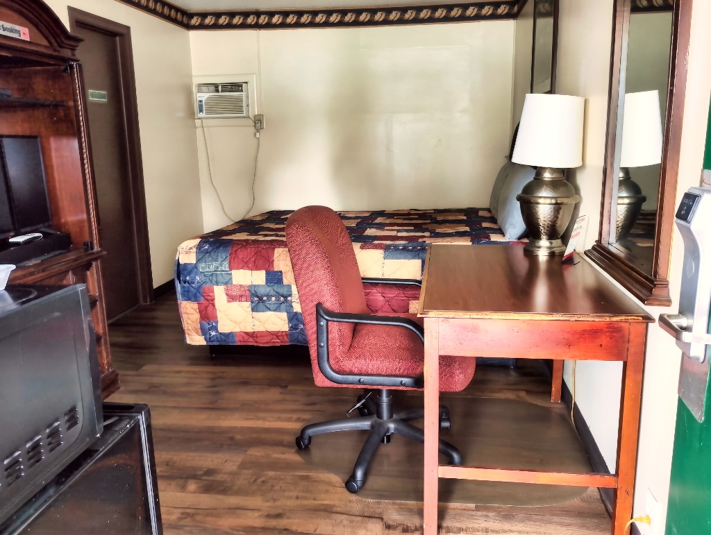 Delta Motel single queen room interior with wood desk, chair, and air conditioner
